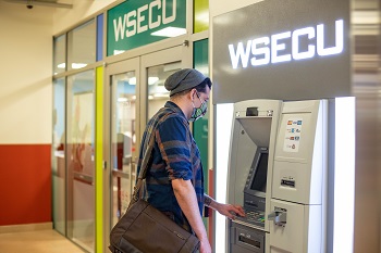 Man wearing a mask and using the ATM in the CUB