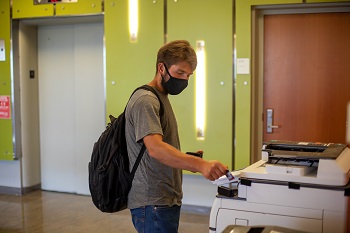 Student wearing a mask and using the printer in the CUB