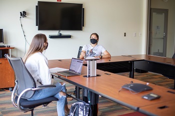 Two girls wearing masks and having a meeting in a CUB meeting room