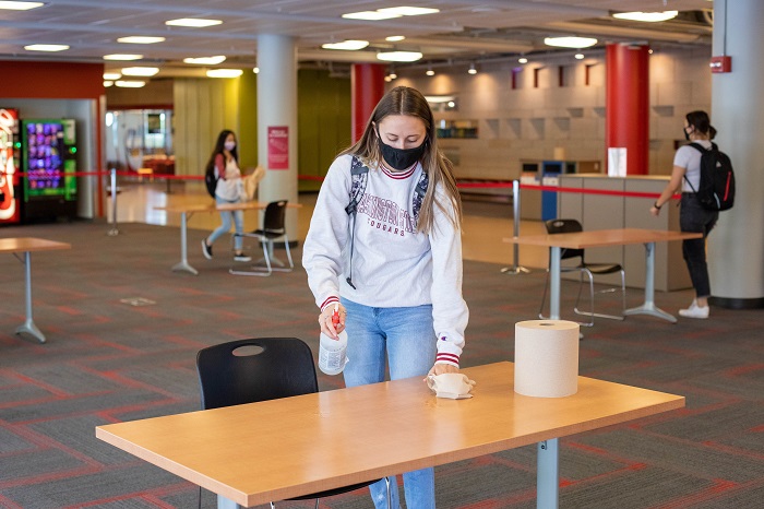 Girl sanitizing a desk in the CUB Lair