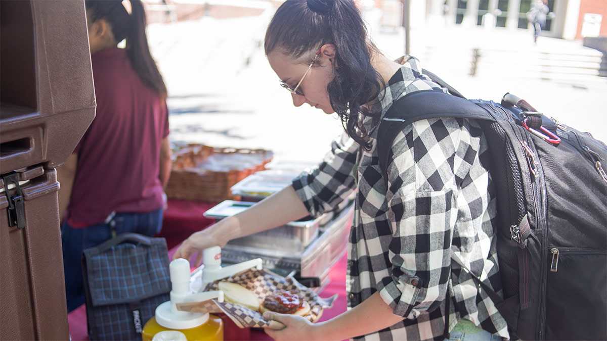 A student puts ketchup on a hamburger