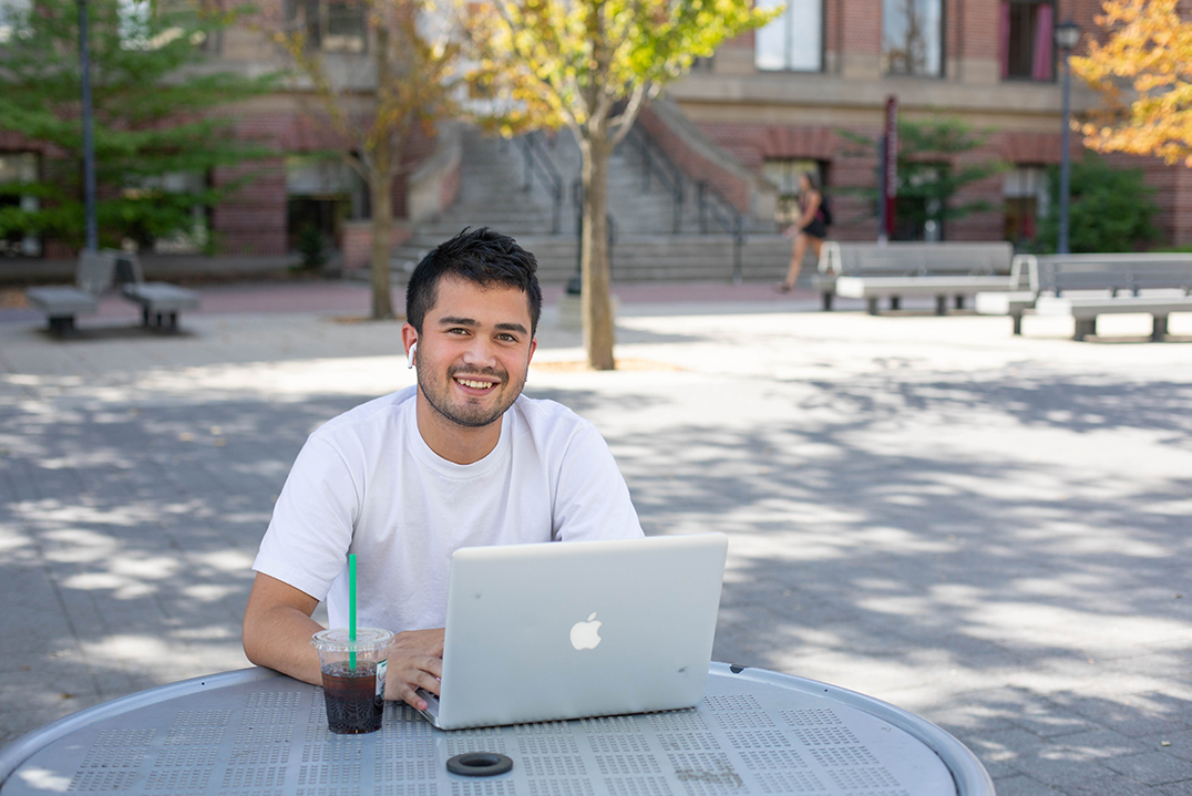 Male student sitting on the mall with computer.